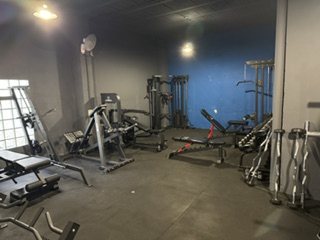 Área de entrenamiento de Serfit con máquinas de musculación, bancos ajustables y espejos para corregir la técnica
