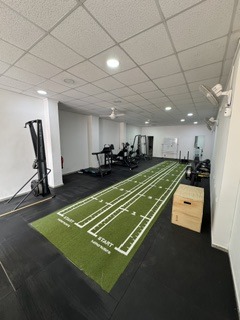 Pista de sprint indoor de Serfit con césped artificial verde, trineos de entrenamiento y zona funcional al fondo